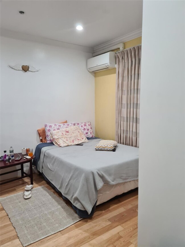 Bedroom featuring crown molding, light wood finished floors, a wall mounted air conditioner, and recessed lighting