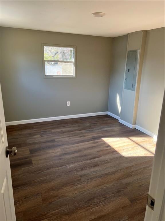 Spare room featuring dark wood finished floors, el