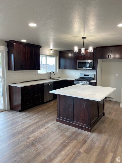 Kitchen with appliances with stainless steel finishes, a sink, light wood finished floors, light countertops, and recessed lighting