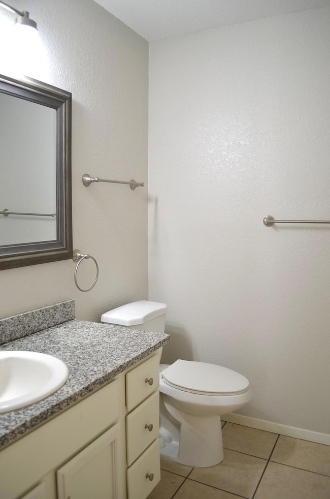 Unit A bathroom with granite vanity and light tile patterned floors