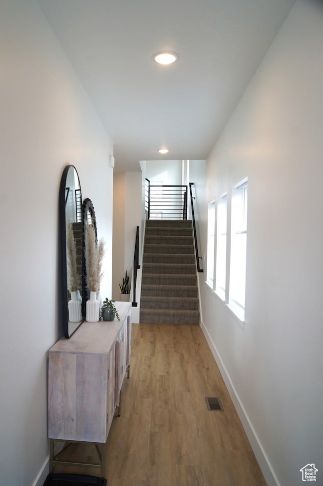 Hallway with stairs and light wood-type flooring