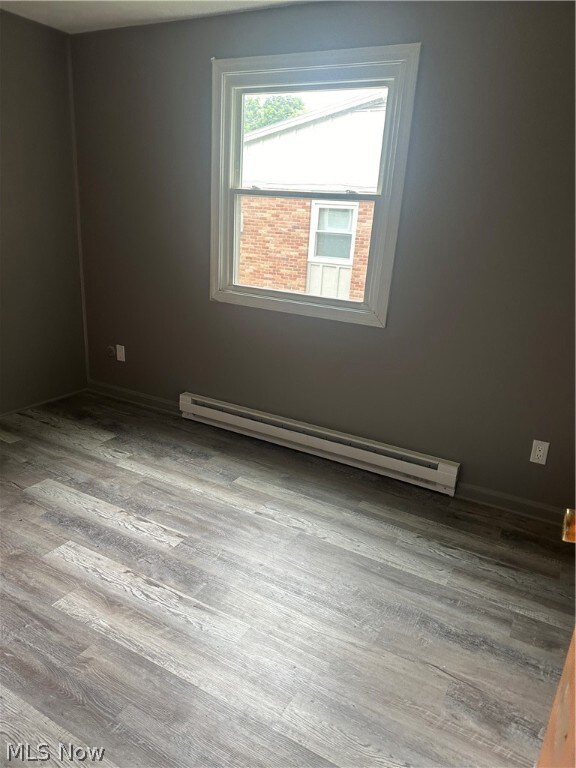 Bedroom featuring a baseboard heating unit and hardwood / wood-style floors