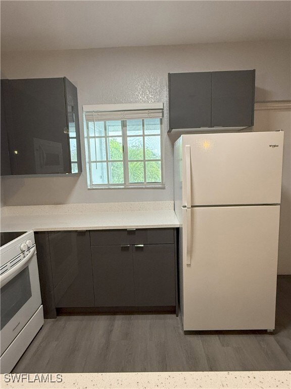 Kitchen featuring white appliances, light wood-sty