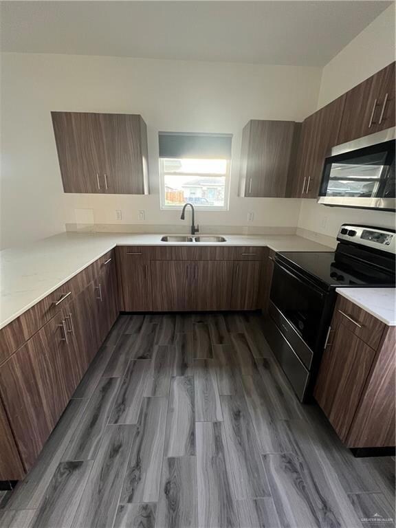 Kitchen with range, light countertops, dark wood-style flooring, and modern cabinets