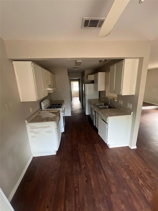 Kitchen with white cabinets, white appliances, and dark wood finished floors