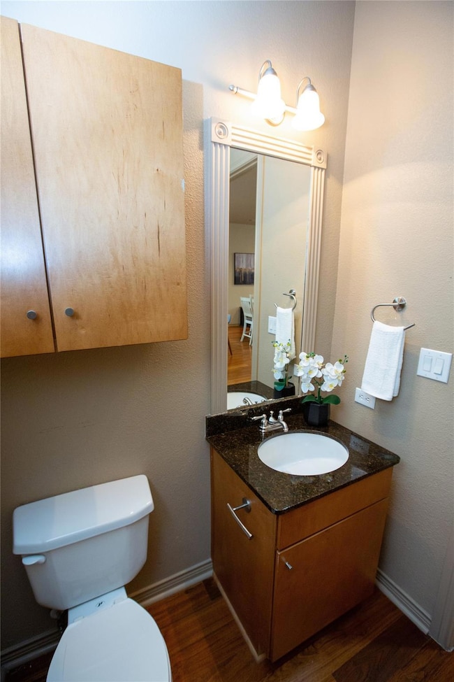 Half bathroom featuring toilet, wood finished floo