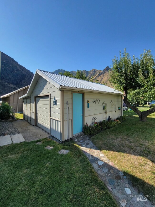View of front of home featuring a mountain view, a metal roof, an outdoor structure, and a front yard