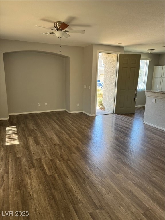 Empty room featuring a ceiling fan, dark wood-type