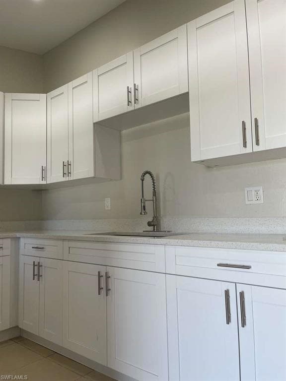 Kitchen with white cabinets, light stone counters, and light tile patterned floors