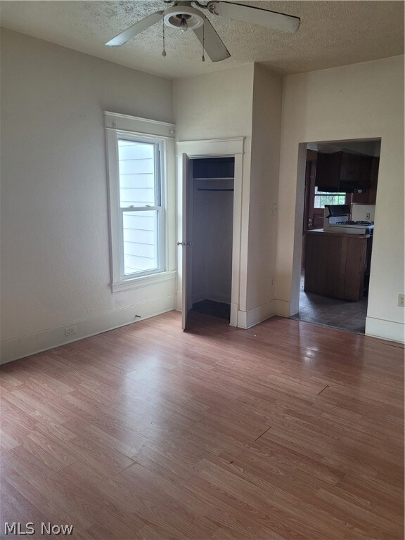 Unfurnished bedroom featuring a textured ceiling, wood-type flooring, and ceiling fan