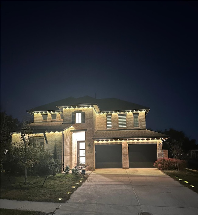 View of front facade featuring brick siding, driveway, and an attached garage