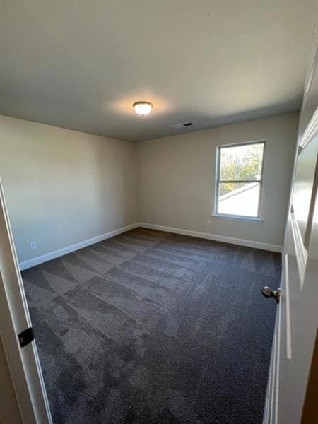 Unfurnished room featuring dark carpet and baseboards