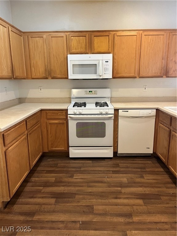 Kitchen featuring white appliances, light countertops, dark wood-style flooring, and brown cabinetry