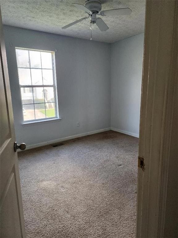 Carpeted empty room with a textured ceiling and a ceiling fan