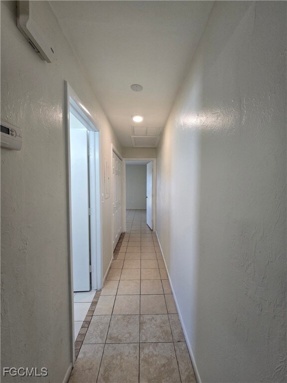 Hallway featuring a textured wall and light tile patterned flooring