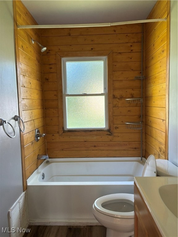 Full bath with shower / bath combination, vanity, dark wood-style floors, and wood walls