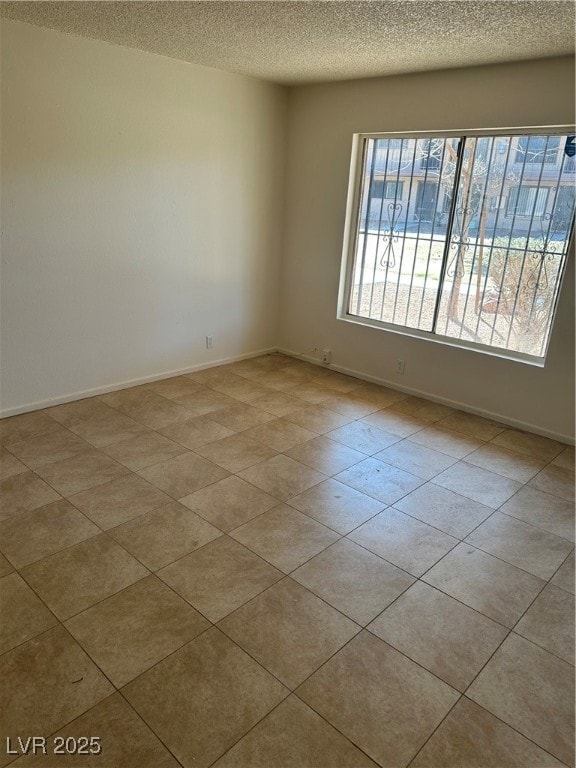 Empty room with a textured ceiling and baseboards