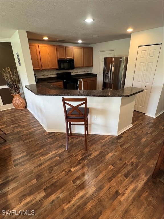 Kitchen featuring fridge, a peninsula, range, dark