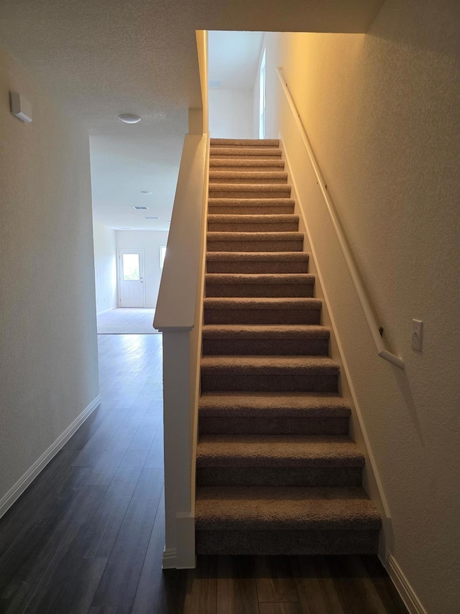 Stairway with wood finished floors and baseboards