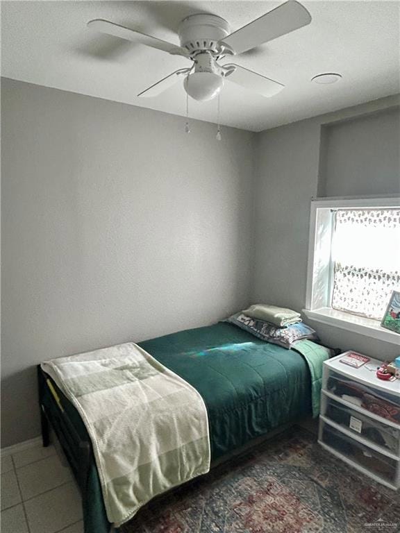 Tiled bedroom with ceiling fan and a textured ceiling