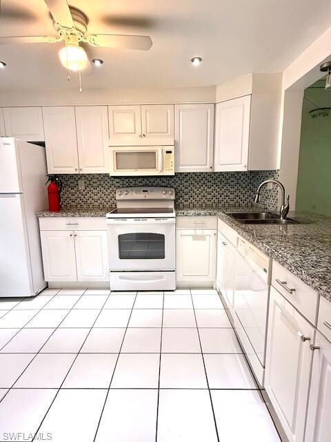 Kitchen with white appliances, a sink, tasteful backsplash, and white cabinets