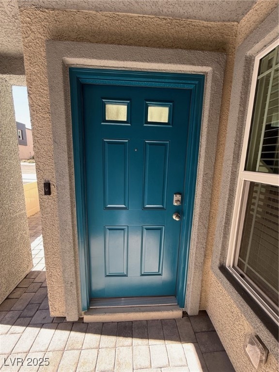 Doorway to property featuring stucco siding