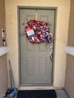 Doorway to property featuring stucco siding