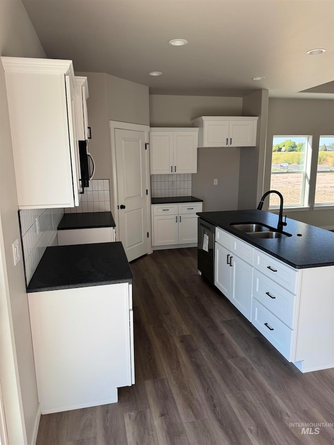 Kitchen featuring decorative backsplash, white cabinetry, an island with sink, dark wood-style floors, and recessed lighting