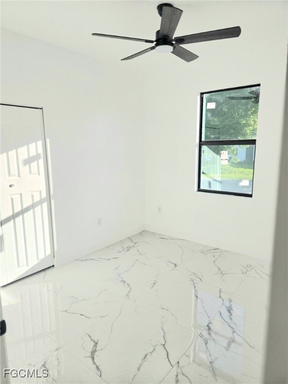 Unfurnished room with light marble finish floors and a ceiling fan