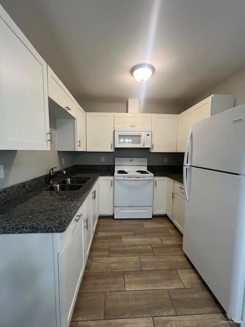 Kitchen featuring white appliances, wood finish floors, and white cabinetry