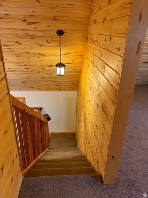 Staircase featuring wooden walls, vaulted ceiling, carpet, and wood ceiling