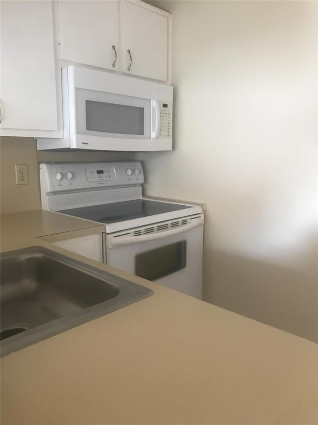 Kitchen with light countertops, white cabinetry, 