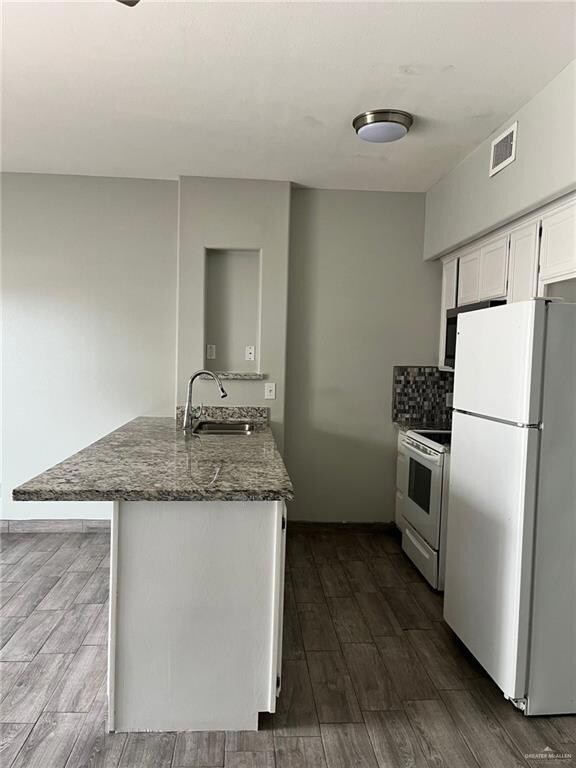 Kitchen featuring white appliances, white cabinetry, dark wood finished floors, and backsplash