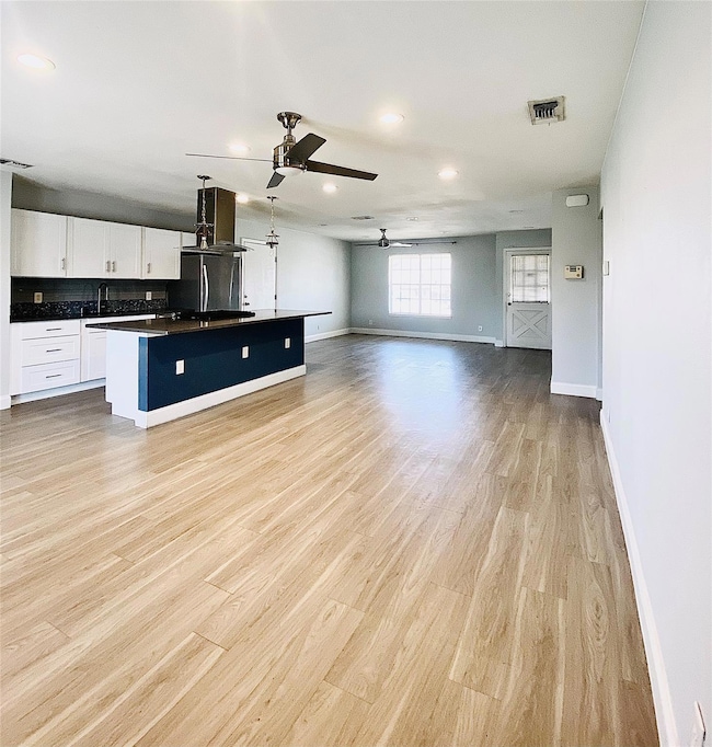 Unfurnished living room with a ceiling fan, baseb