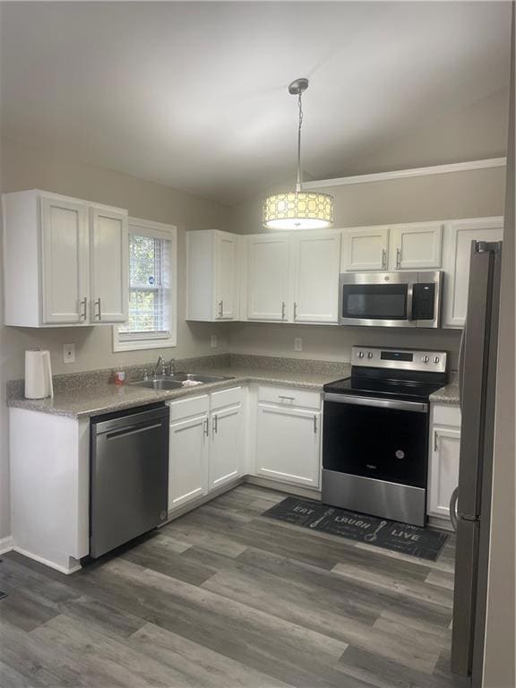 Kitchen featuring stainless steel appliances, vaulted ceiling, and white cabinets