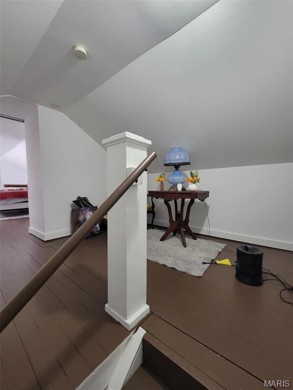 Stairway with lofted ceiling, baseboards, and wood-type flooring