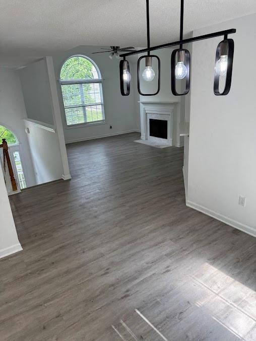View living room with a textured ceiling, a fireplace with flush hearth, wood finished floors, baseboards, and ceiling fan