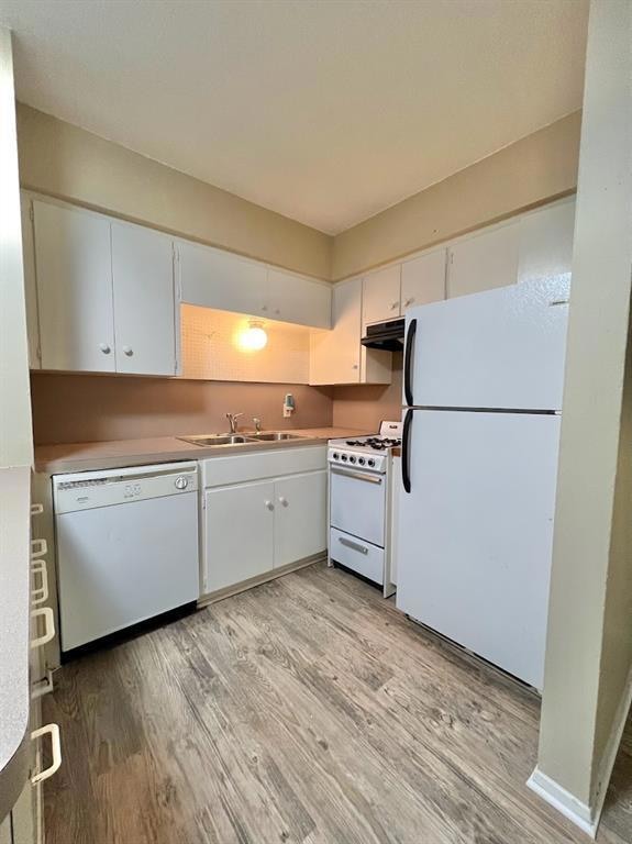 Kitchen with white appliances, white cabinetry, light wood finished floors, and range hood