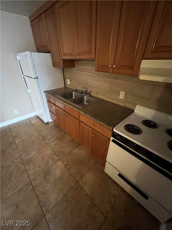 Kitchen with white appliances, a sink, tile patter