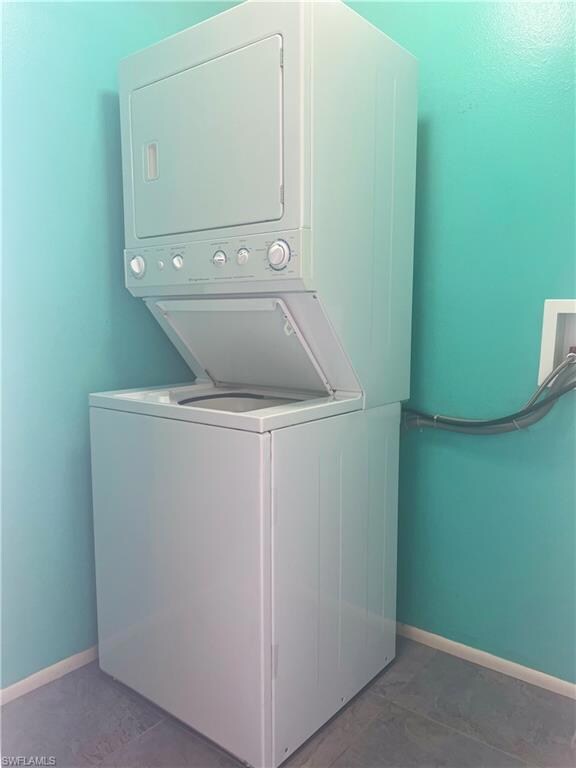 Laundry area featuring stacked washing machine and dryer and baseboards