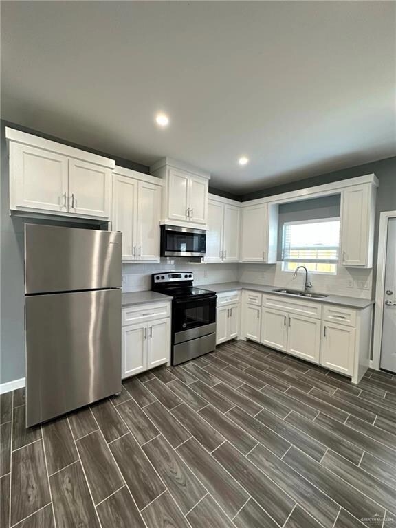 Kitchen with white cabinets, sink, and tasteful backsplash