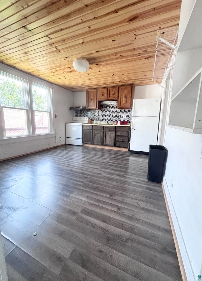 Kitchen featuring freestanding refrigerator, brown cabinetry, range with electric stovetop, wood ceiling, and dark wood-type flooring