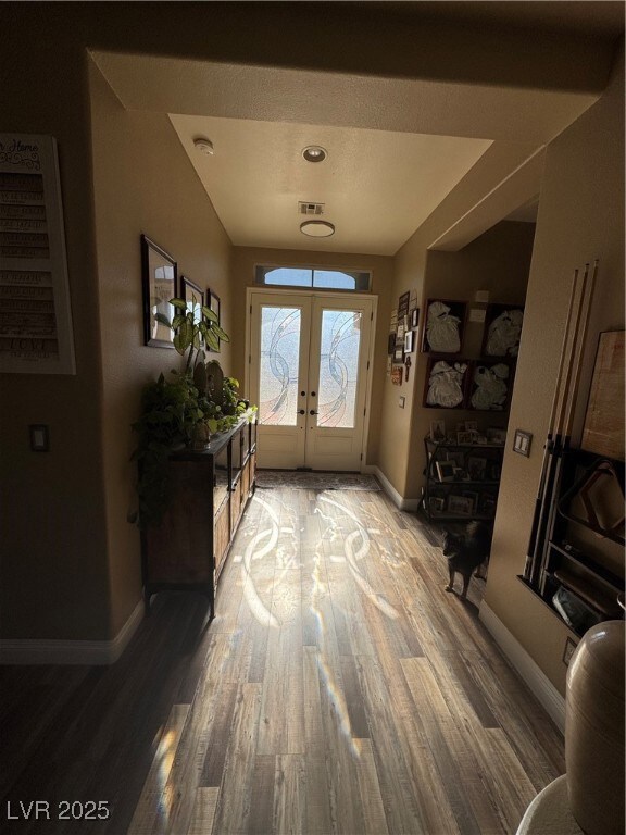 Foyer with french doors, baseboards, and wood fini
