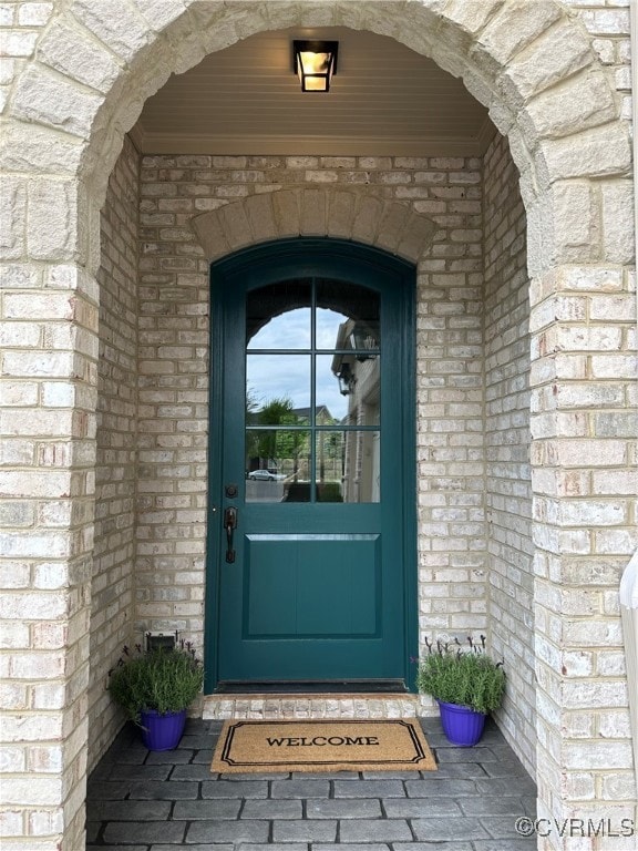 View of exterior entry with brick siding and stone