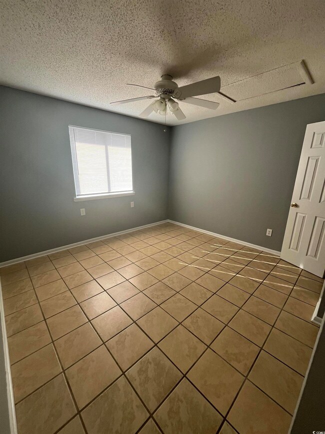 Empty room with ceiling fan, tile patterned floori