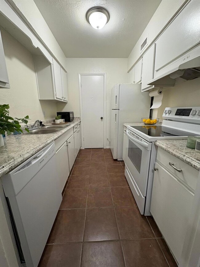 Kitchen with sink, a textured ceiling, dark tile p