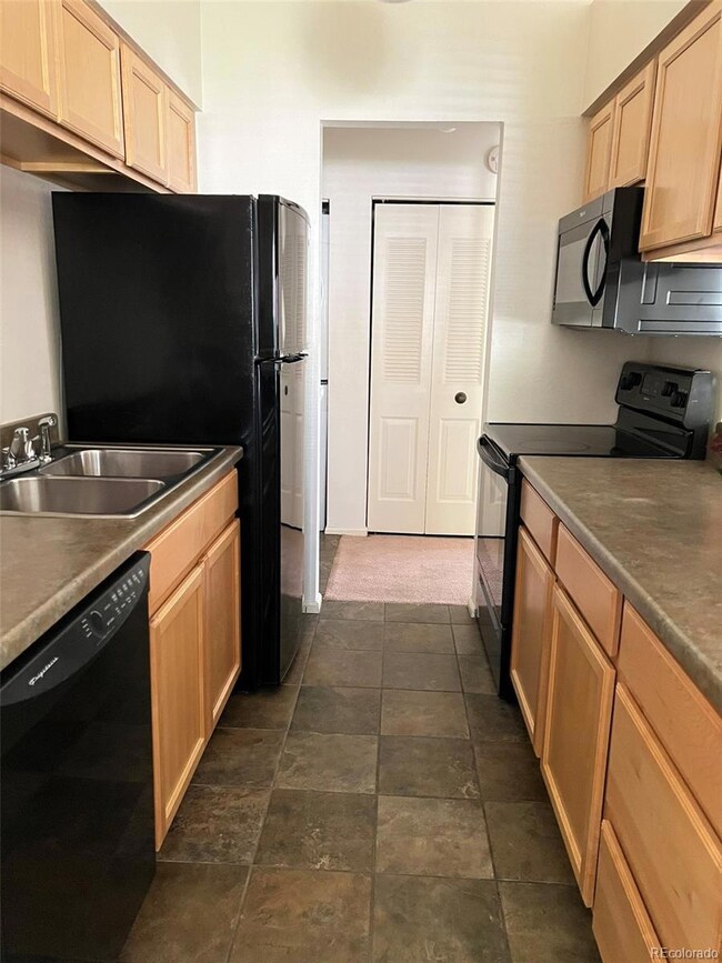 Kitchen with maple cabinets, black appliances and ceramic slate tile floors