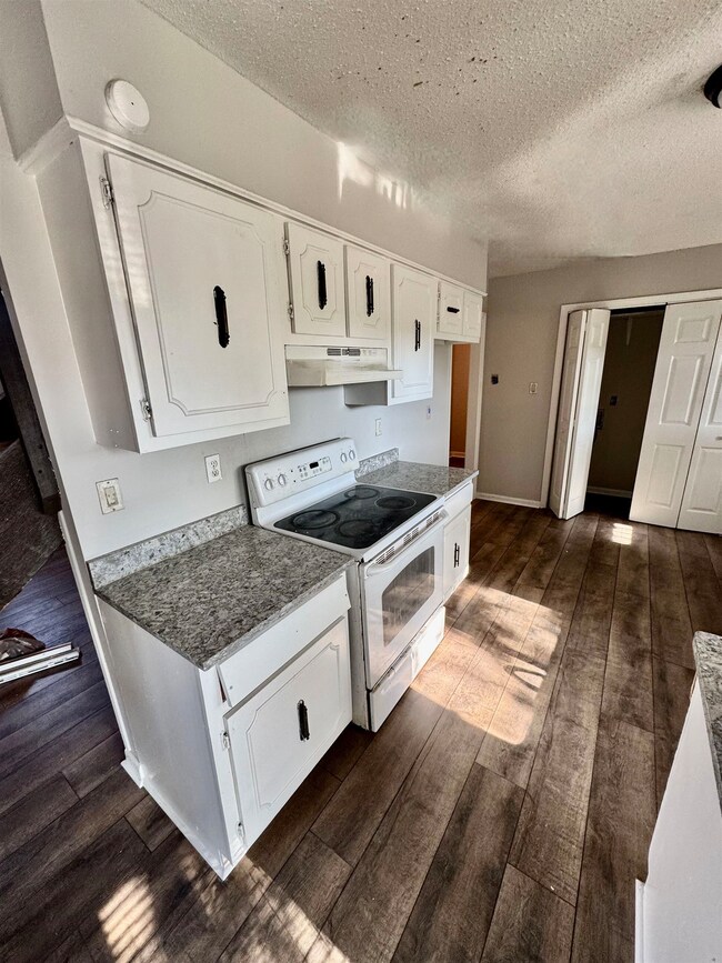 Kitchen with white cabinetry, electric range, a te