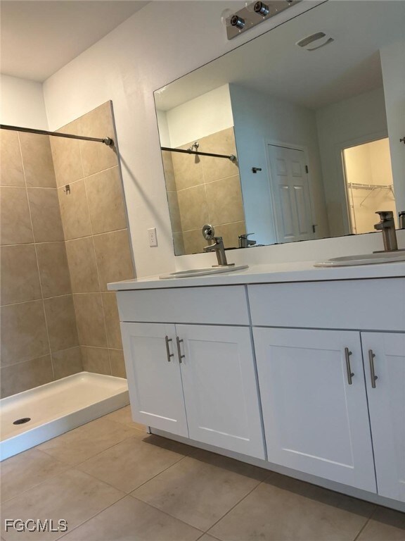 Bathroom with a shower stall, double vanity, and light tile patterned floors