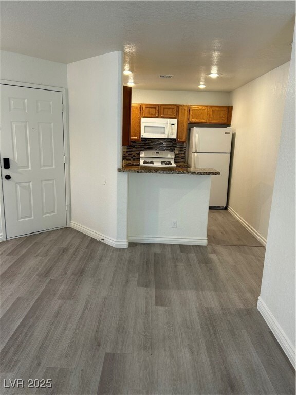 Kitchen with refrigerator, stove, brown cabinetry,